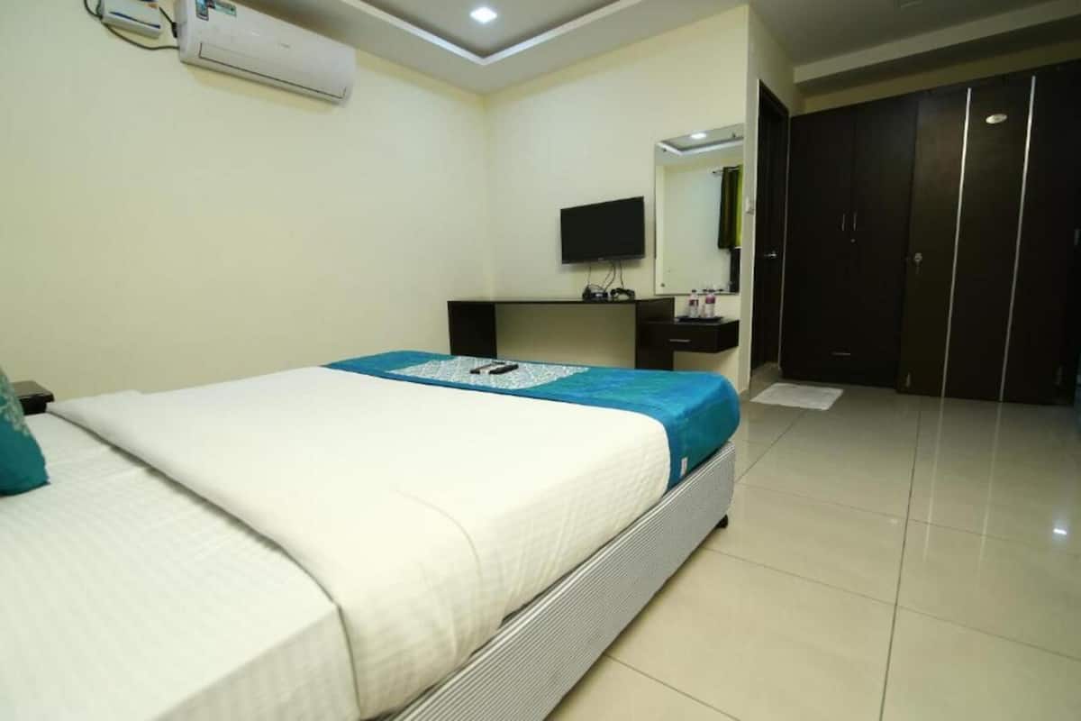 Quarto de hotel com cama, secretária, televisão e guarda-roupa.