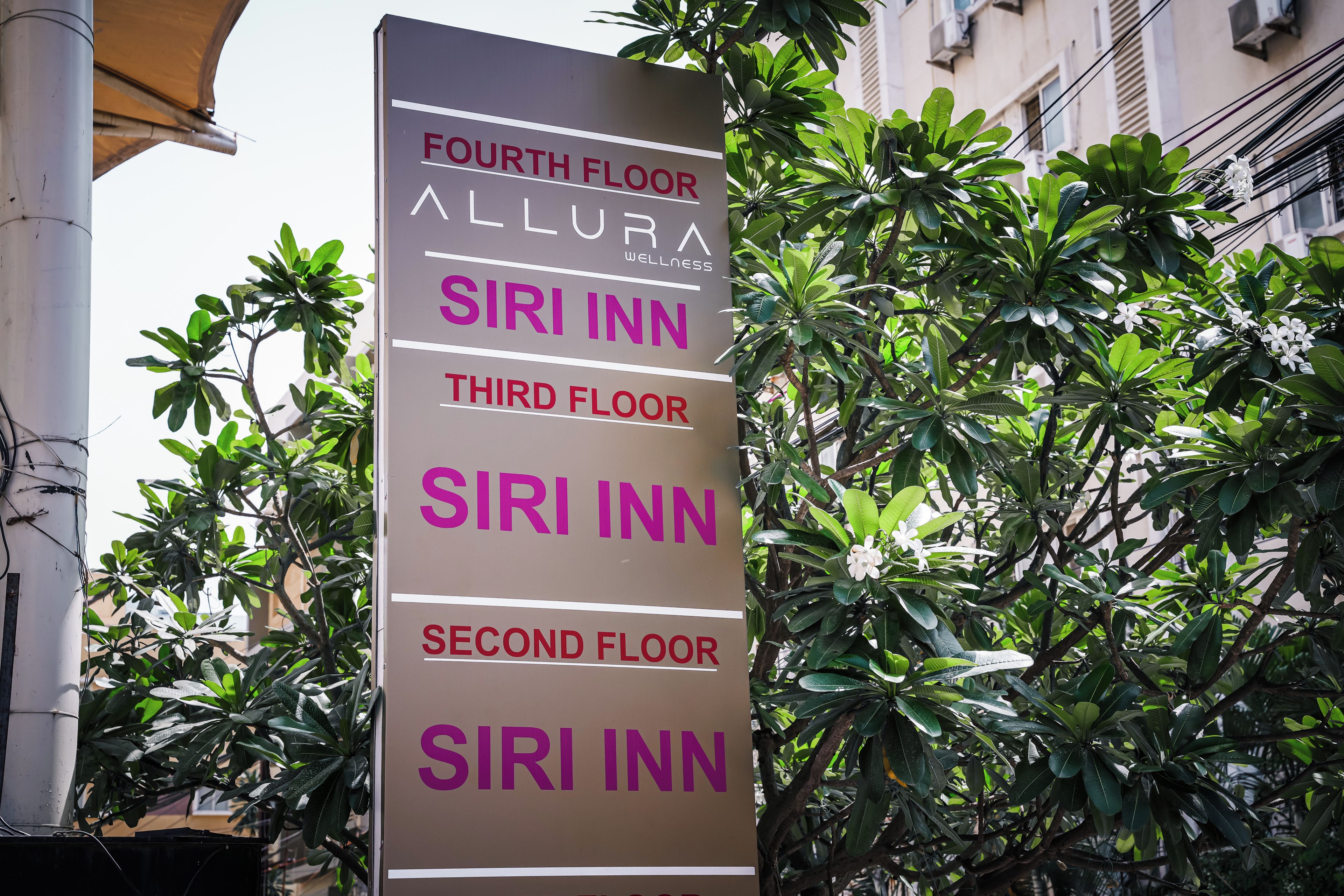 Señal vertical con información de los pisos de un hotel, incluyendo 'Cuarto Piso Allura', 'Tercer Piso Siri Inn' y 'Segundo Piso Siri Inn'.