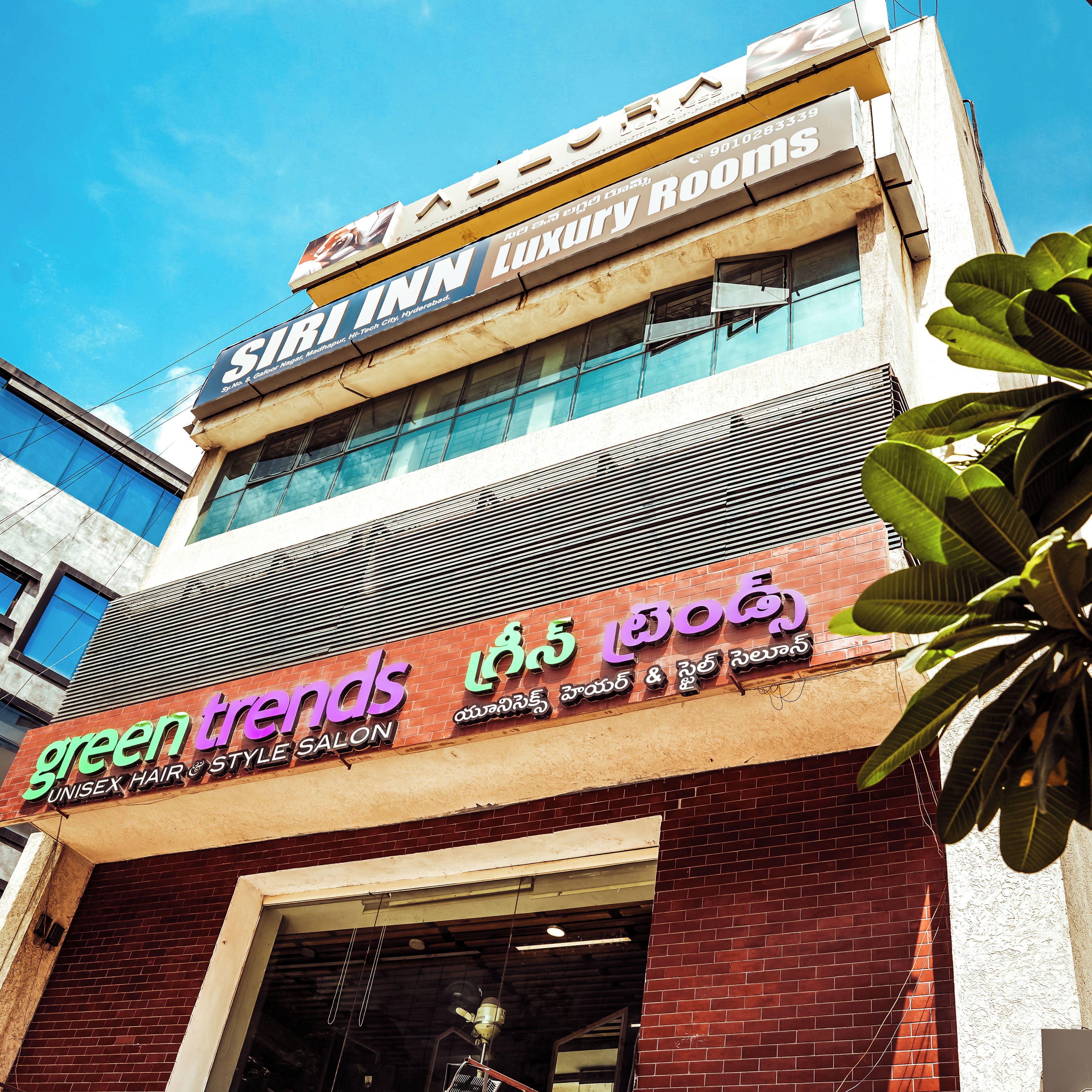 Un edificio con un cartel que indica 'Siri Inn Luxury Rooms' y 'Green Trends Unisex Hair & Style Salon'.