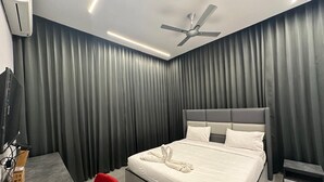 A modern hotel room with a large bed, grey curtains, a ceiling fan, and a flat-screen TV. - Hotel Siri Inn (Hyderabad)