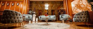 A lobby with two tufted armchairs, a round coffee table, and a sofa. - Regal Inn Badamdar (Baku)