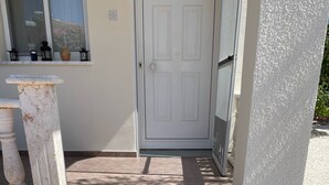 A wooden deck leading to a white door with a window above it. - Coral Bay Bungalow (Coral Bay)