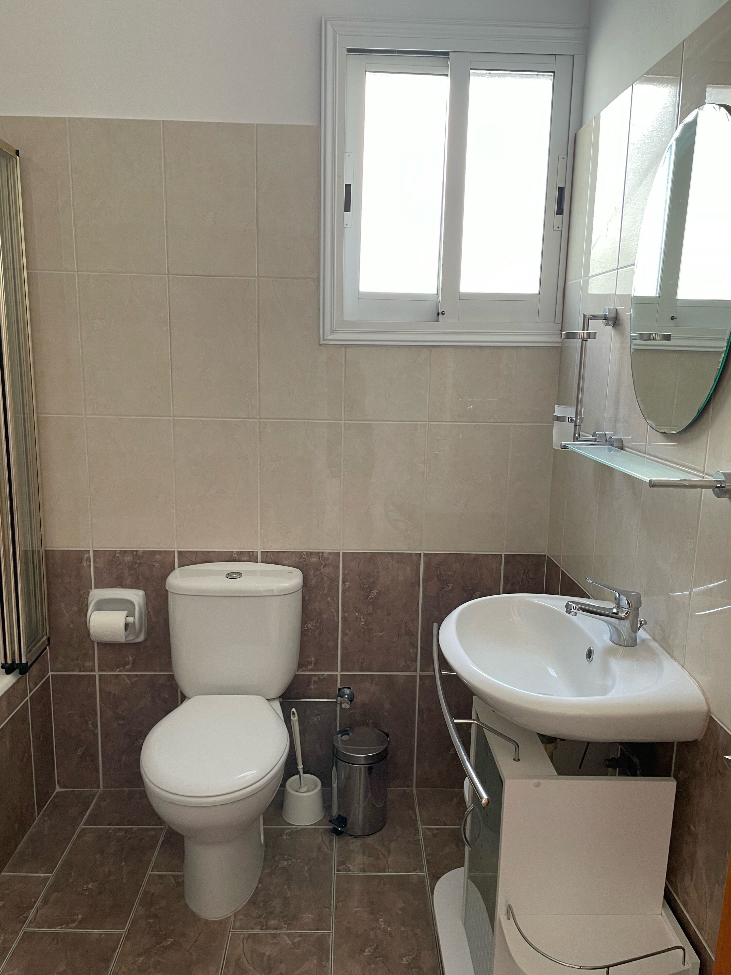 Une salle de bain avec des toilettes, un lavabo et une fenêtre.