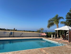 Ein Pool mit Meerblick, eine überdachte Sitzgelegenheit und ein Schild mit der Aufschrift 'POOL RULES'.