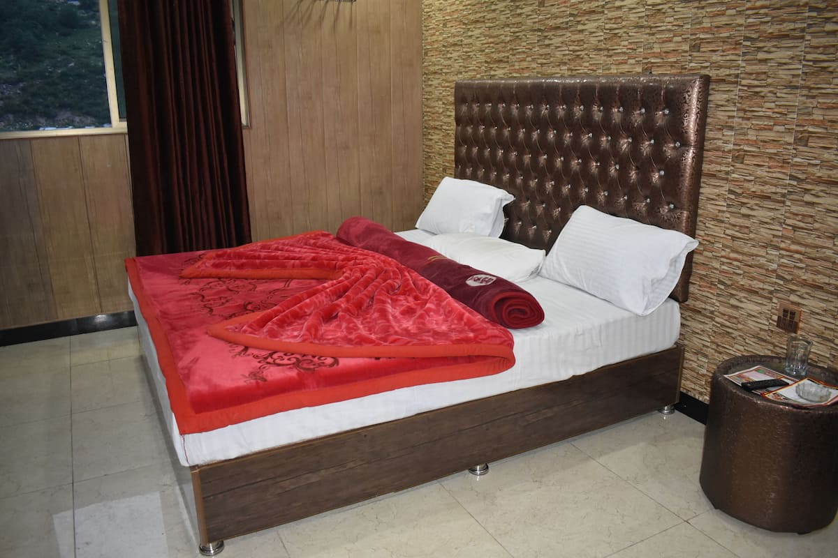 Ein ordentlich bezogenes Bett mit roter Decke und Kissen, ein hölzerner Kopfteil und eine Wand mit Steinmuster.