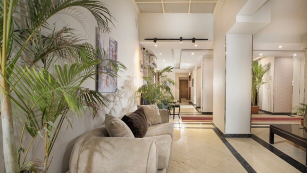 A spacious lobby with a beige sofa, potted plants, and a polished floor. - Vibotel Residence Hotel Apartments (New Cairo)