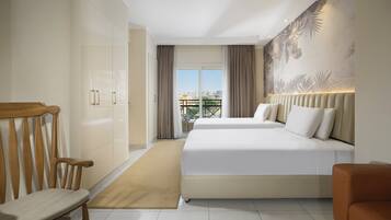 Habitación de hotel con una cama grande, una silla de madera, un sofá y vistas a la ciudad por la ventana.