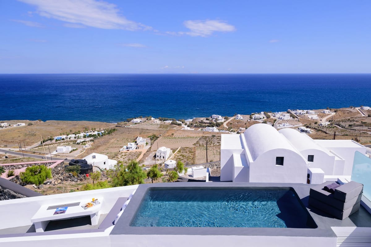 A pool area with a view of the sea and white buildings.