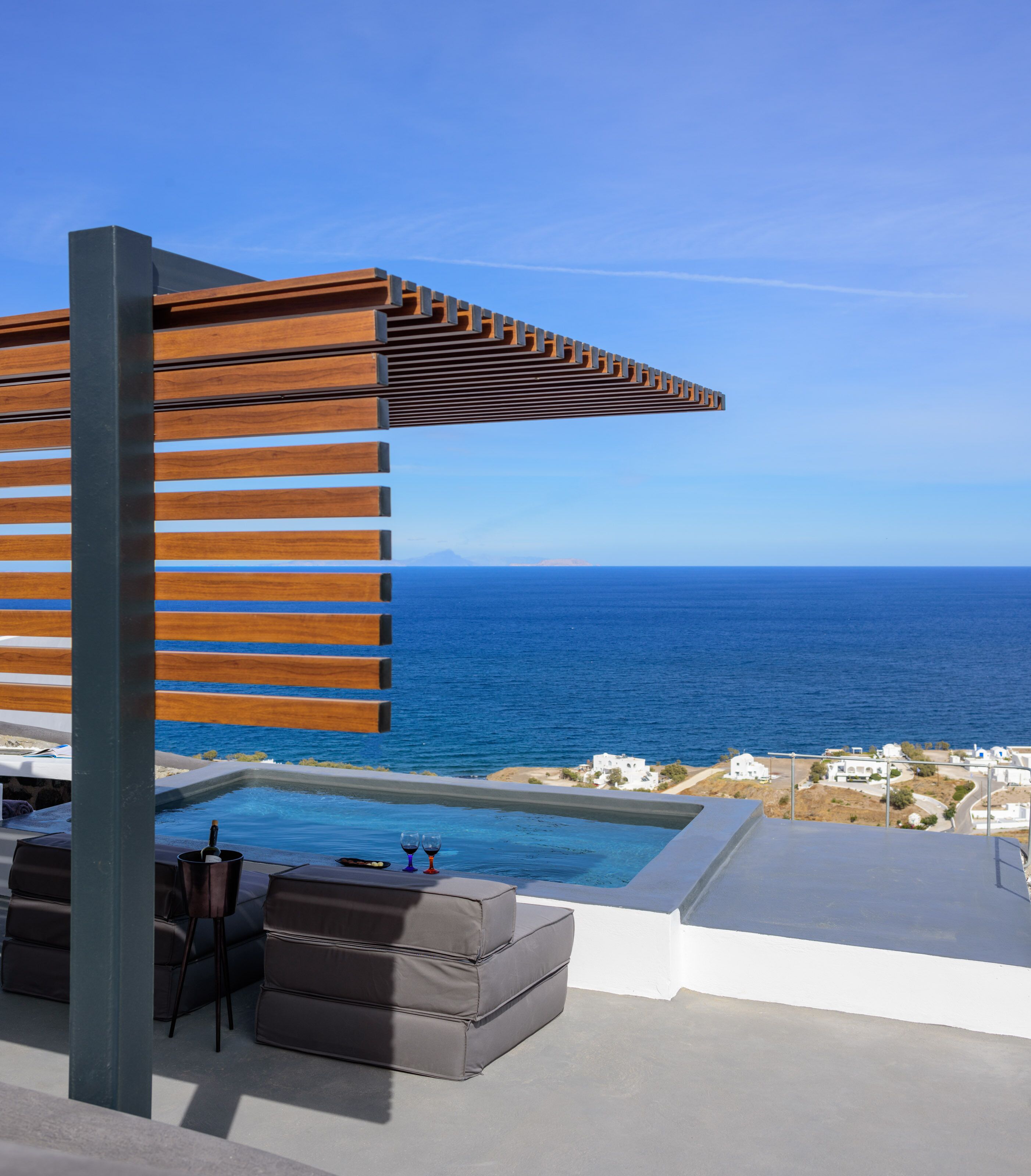 A poolside area with a wooden pergola, lounge chairs, and a view of the ocean.