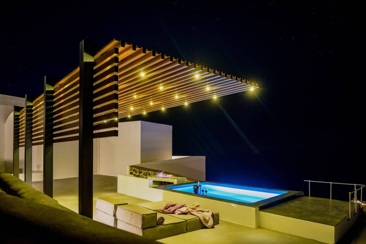 A modern outdoor pool area with a minimalist design, including a pool, seating, and a pergola with string lights.