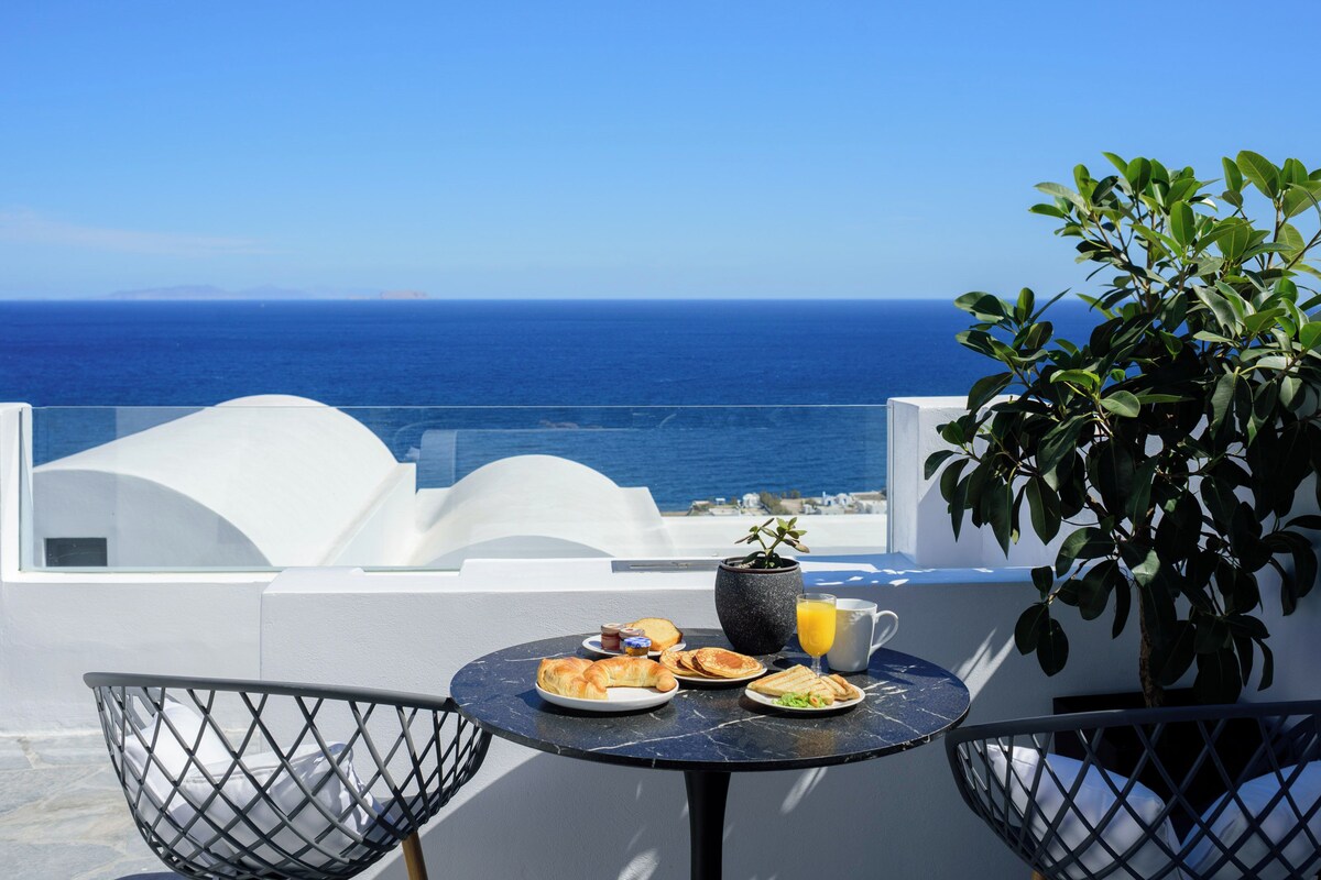 A table with breakfast items and a view of the sea.