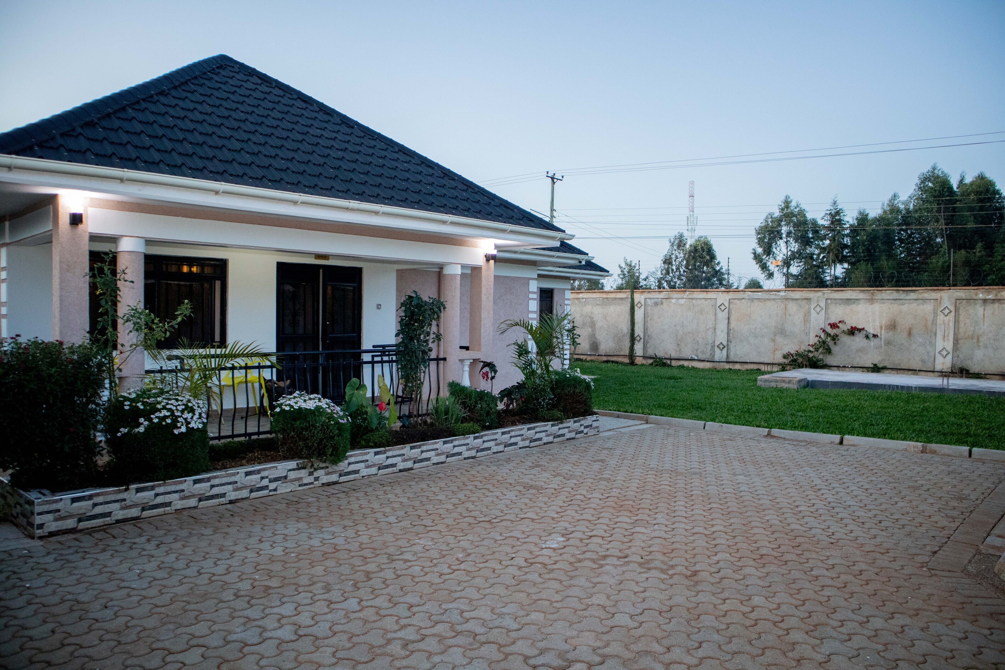 A two-story house with a dark tiled roof, a paved driveway, and a well-maintained lawn.