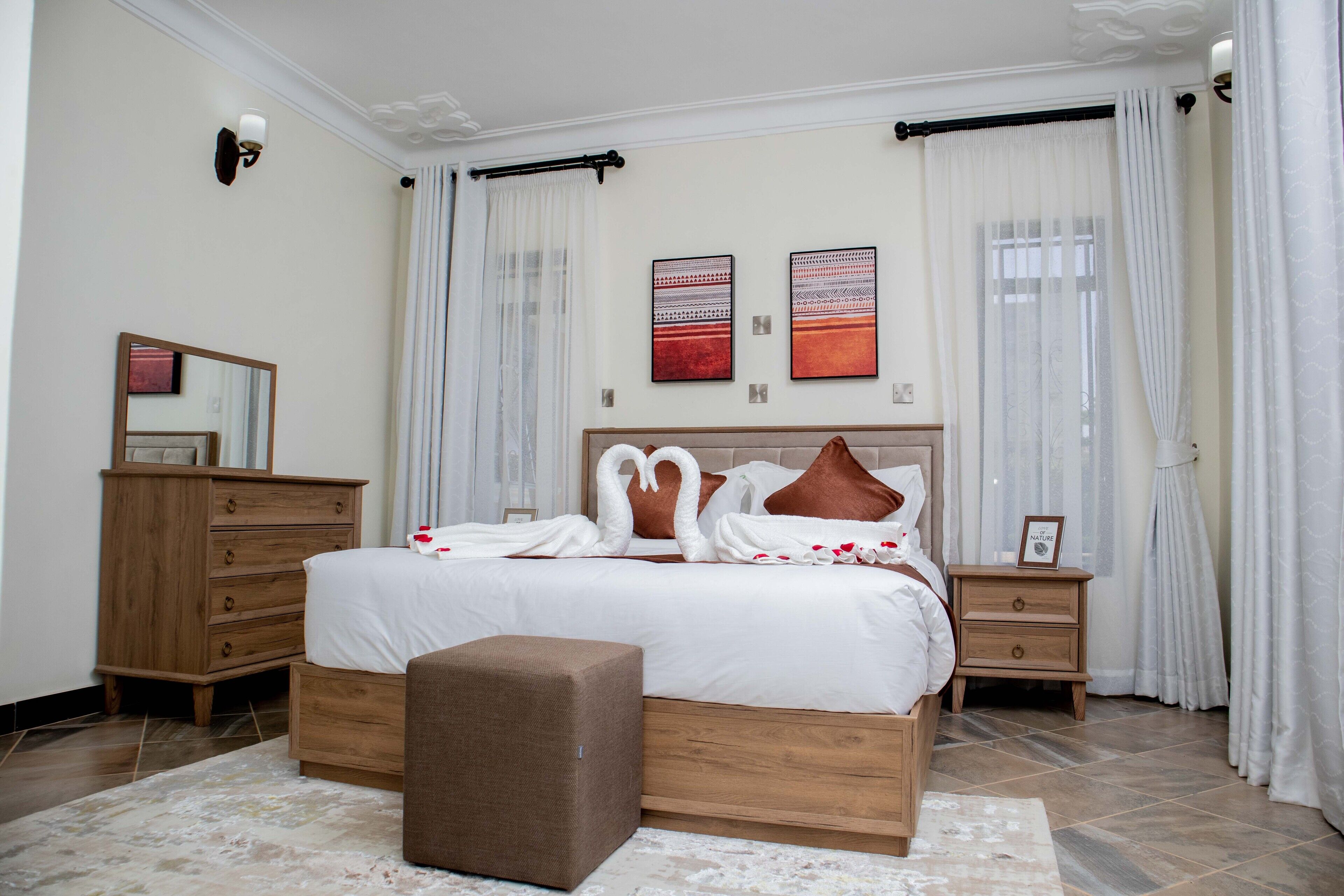 Une chambre à coucher bien rangée, avec un grand lit, une commode en bois, une table de chevet et un miroir.