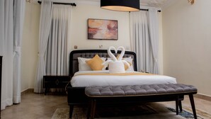 A bedroom with a bed, a bedside table, a bench, a painting, and curtains. - Stay.Plus Blueberry Villas Eldoret (Eldoret)