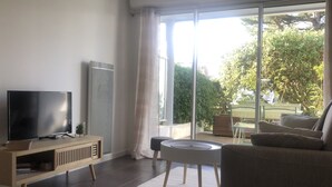 A modern living room with a flat-screen TV, a large window, and a view of the outdoors. - VANNES CENTER QUIET-COZY-T2 WITH PRIVATE PARKING-TERRACE-WIFI (Vannes)