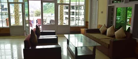 Un salón espacioso con una mesa de centro de vidrio, un sofá con cojines y vistas a un balcón con mobiliario exterior.