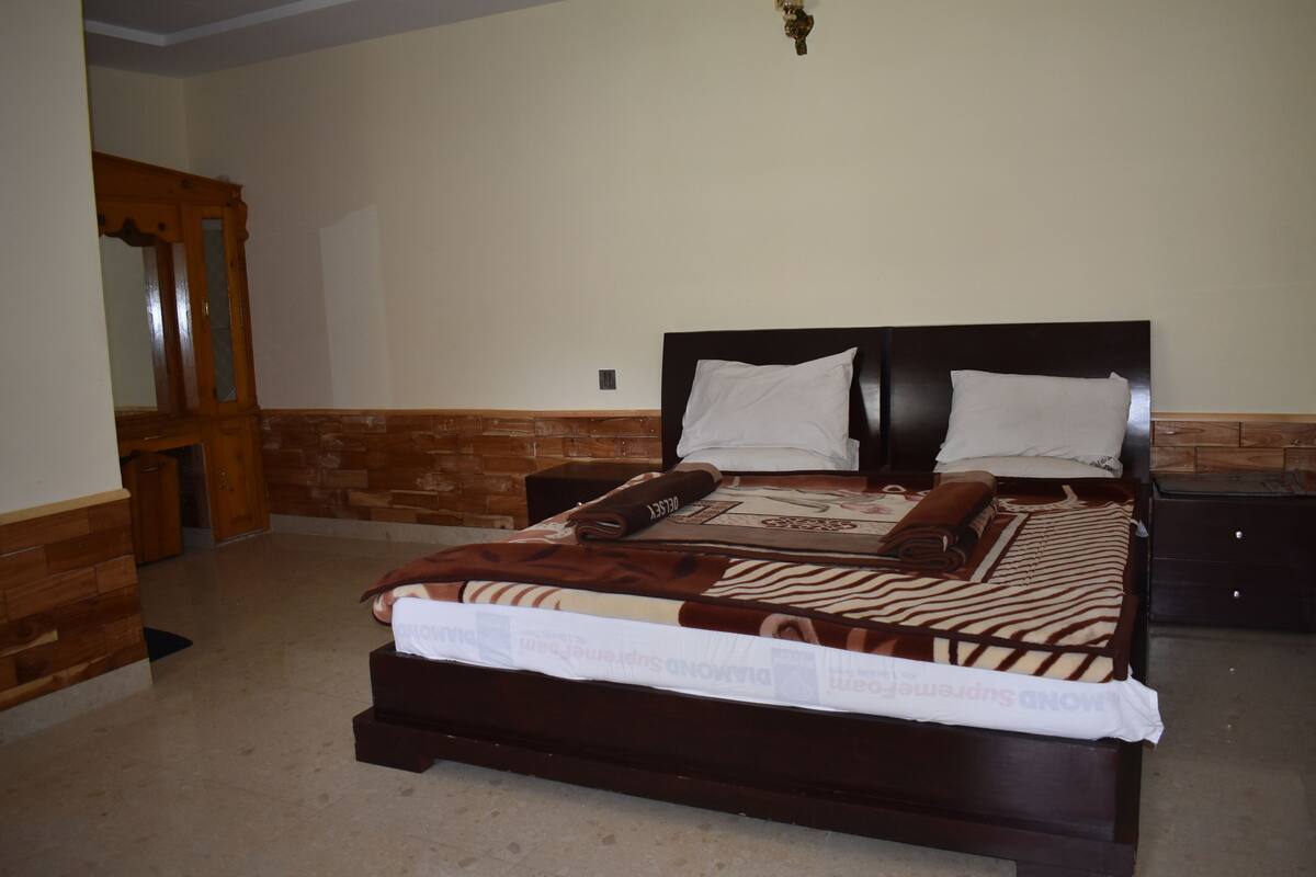 Un dormitorio con cabecera de madera, un espejo grande y una cama con manta a rayas.
