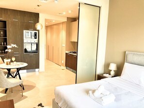 A modern hotel room with a bed, a desk, and a kitchenette. - Superior Studio in Park View JVC (Dubai)