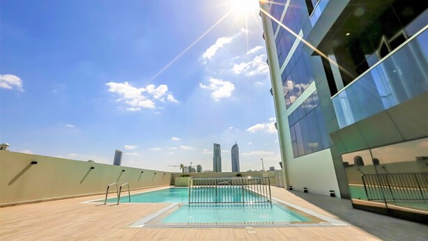 Une piscine sur le toit offrant une vue dégagée sur les grat-ciel de la ville, entourée d’immeubles modernes.