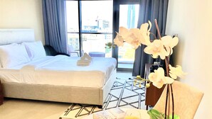 Une chambre d’hôtel avec un lit, une table sur laquelle se trouve un verre de jus d’orange, un livre et une plante en pot.