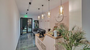 A hotel reception area with a modern design, including a reception desk, a sofa, and hanging pendant lights. - Siars Hotel (Ksamil)