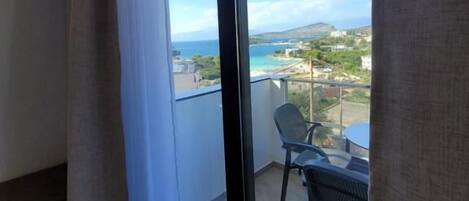 A balcony with a view of the sea and a chair.