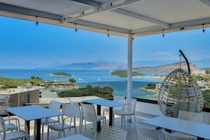 Una terrazza con tavolo e sedie, vista sulla costa, montagne e mare.