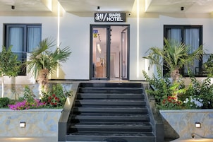 L'ingresso di un hotel con un cartello che riporta "SIARS HOTEL", una scalinata che conduce all'entrata e un giardino con diverse piante e fiori.