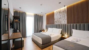 A modern hotel room with a large bed, a desk, and a wardrobe.