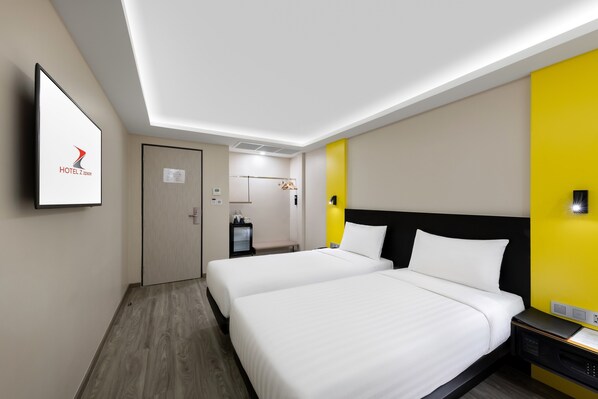 A hotel room with two beds, a flat-screen TV, a desk, and a bright yellow accent wall. - Hotel Z Zpaze (Bangkok)