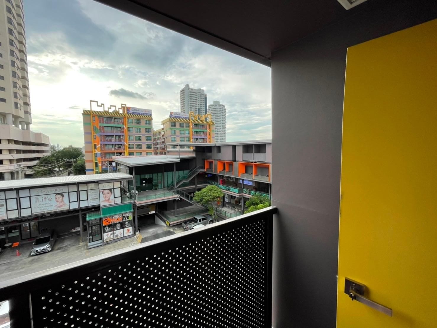 A view from a window overlooking a cityscape with multi-story buildings and a parking area.