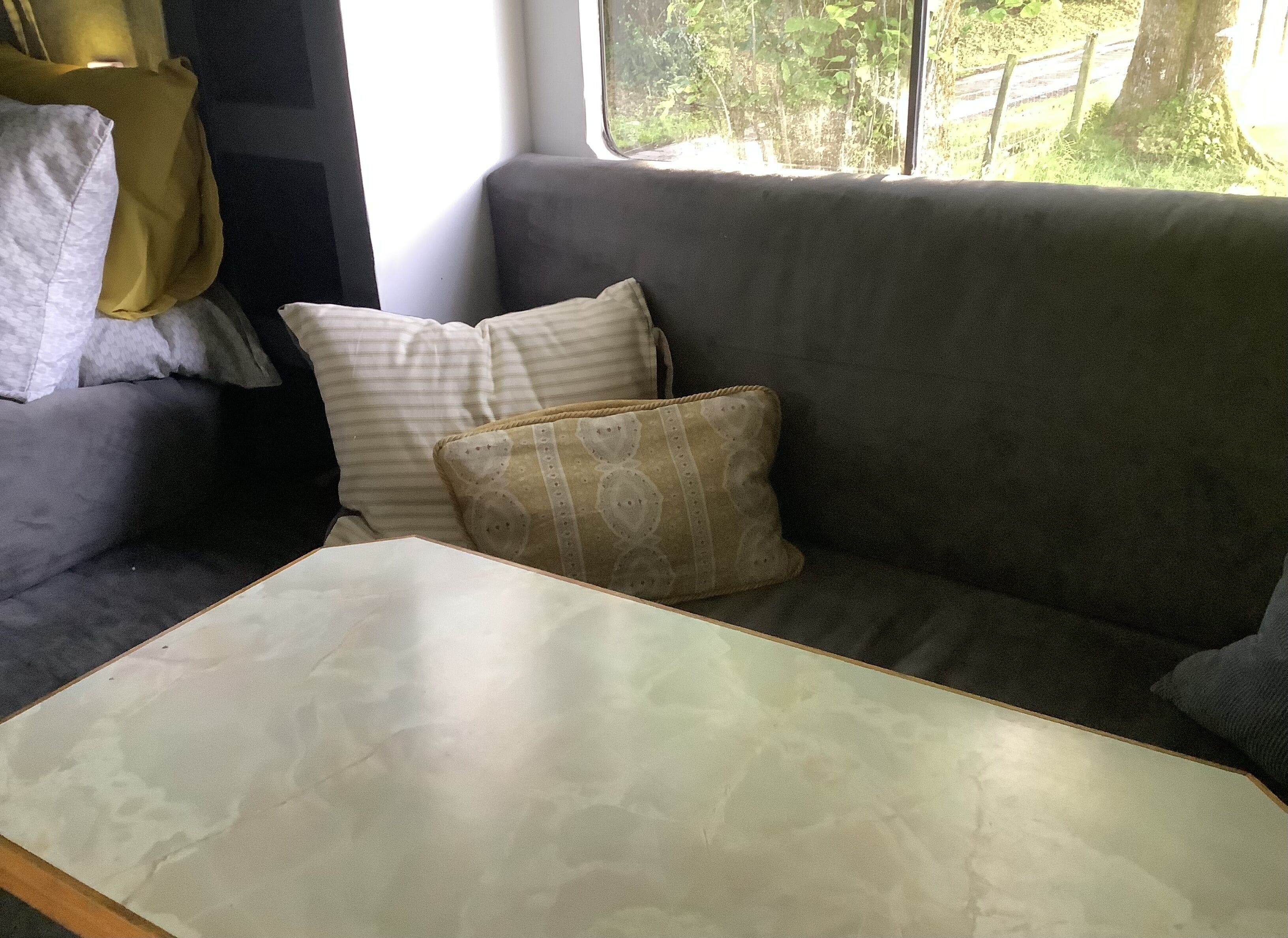 A gray sofa with patterned cushions and a white table in a room with a window.