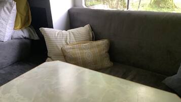 A gray sofa with patterned cushions and a white table in a room with a window.