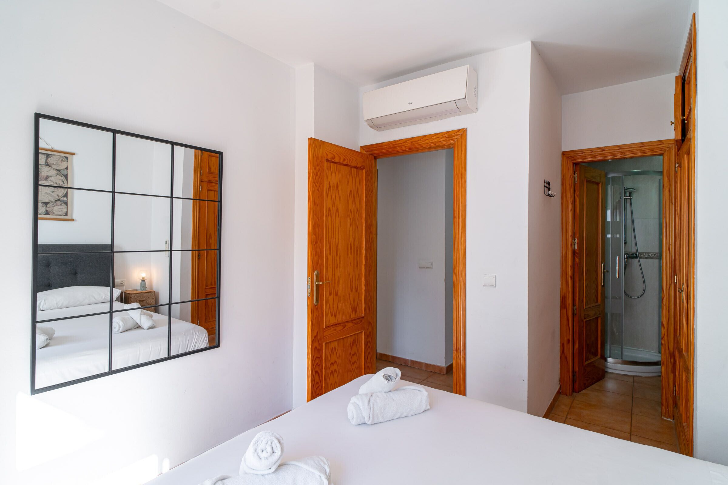 Een hotelkamer met een bed, een spiegel, een kledingkast en een douchehoek.