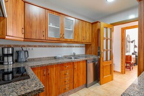 A kitchen with wooden cabinets, a granite countertop, a coffee maker, and a dishwasher.