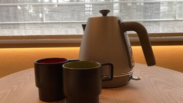 A coffee maker on a wooden table with two mugs.