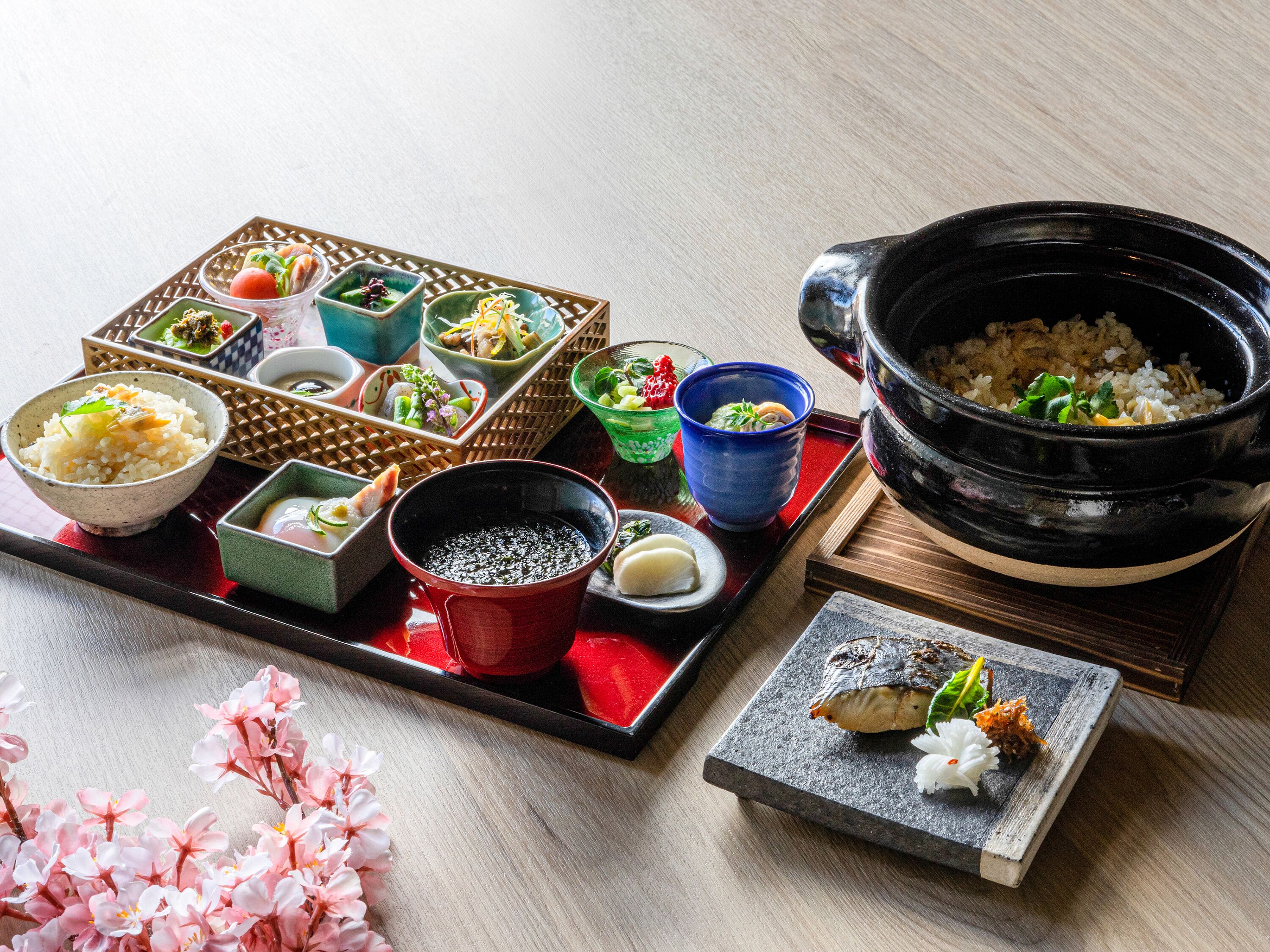 Een traditionele Japanse maaltijdopstelling met diverse gerechten en een grote zwarte pot.