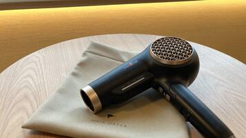 A hair dryer on a round wooden table with a beige cloth.