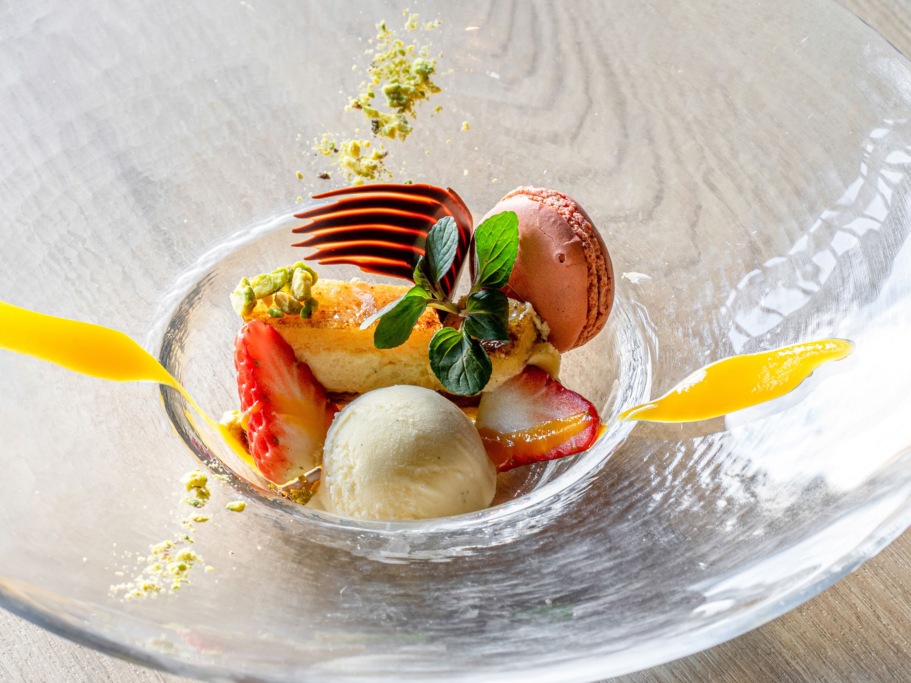 A dessert with strawberries, ice cream, and a pastry in a glass bowl.