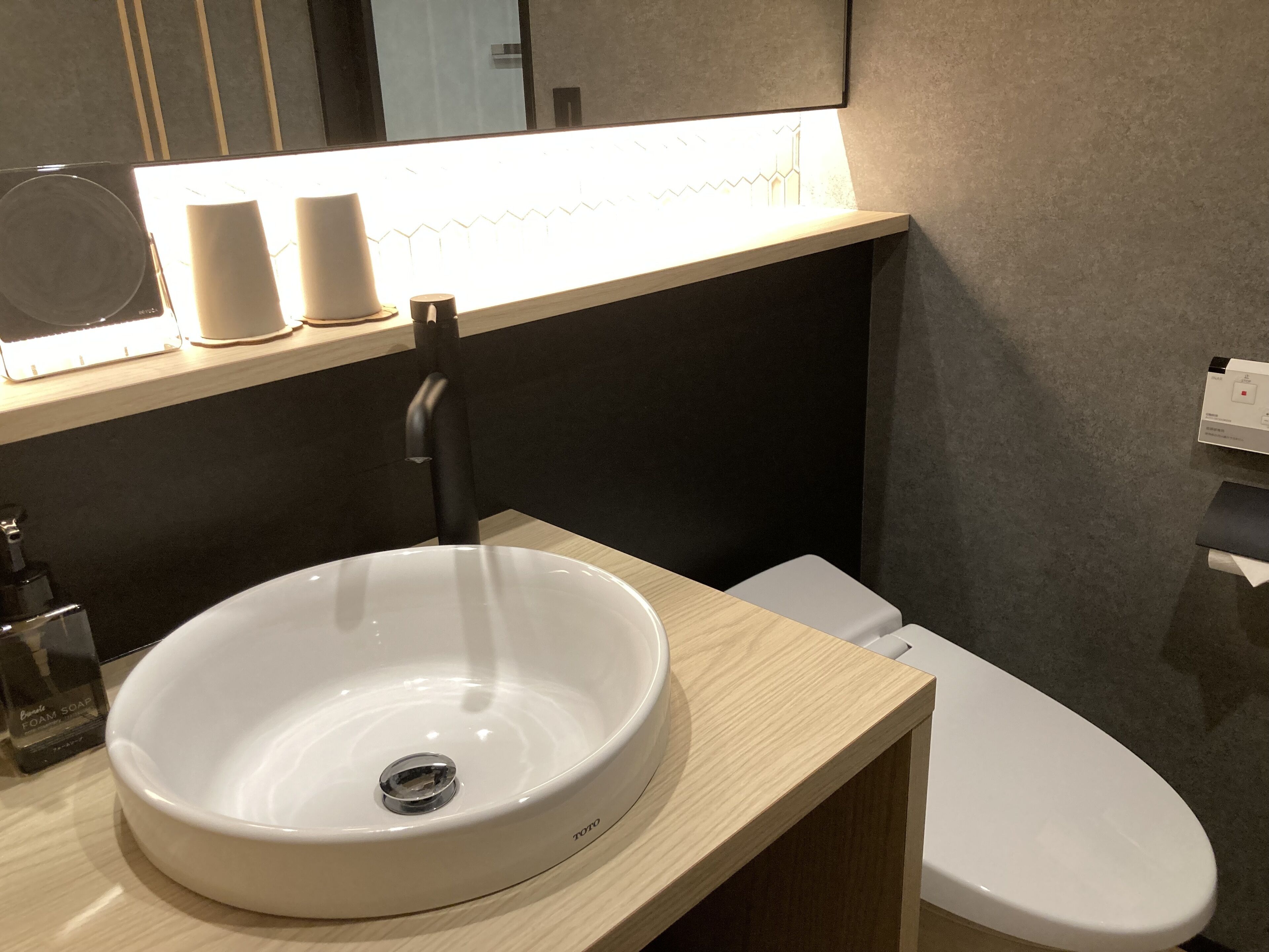 Een moderne badkamer met een wit wastafel, een zwarte kraan en een toilet.