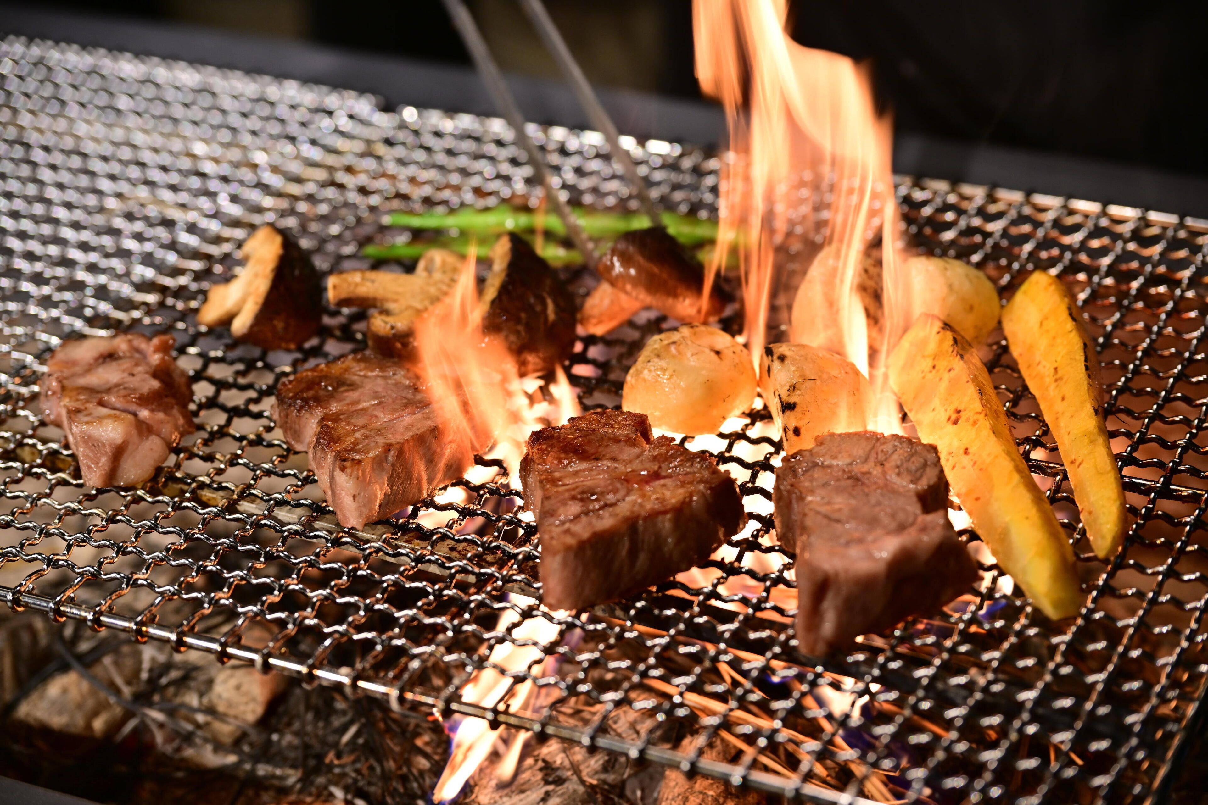 A grill with various meats and vegetables being cooked.