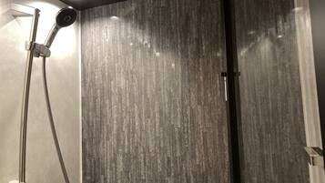 A modern shower with a wooden-texture wall, a handheld showerhead, and a wall-mounted faucet.