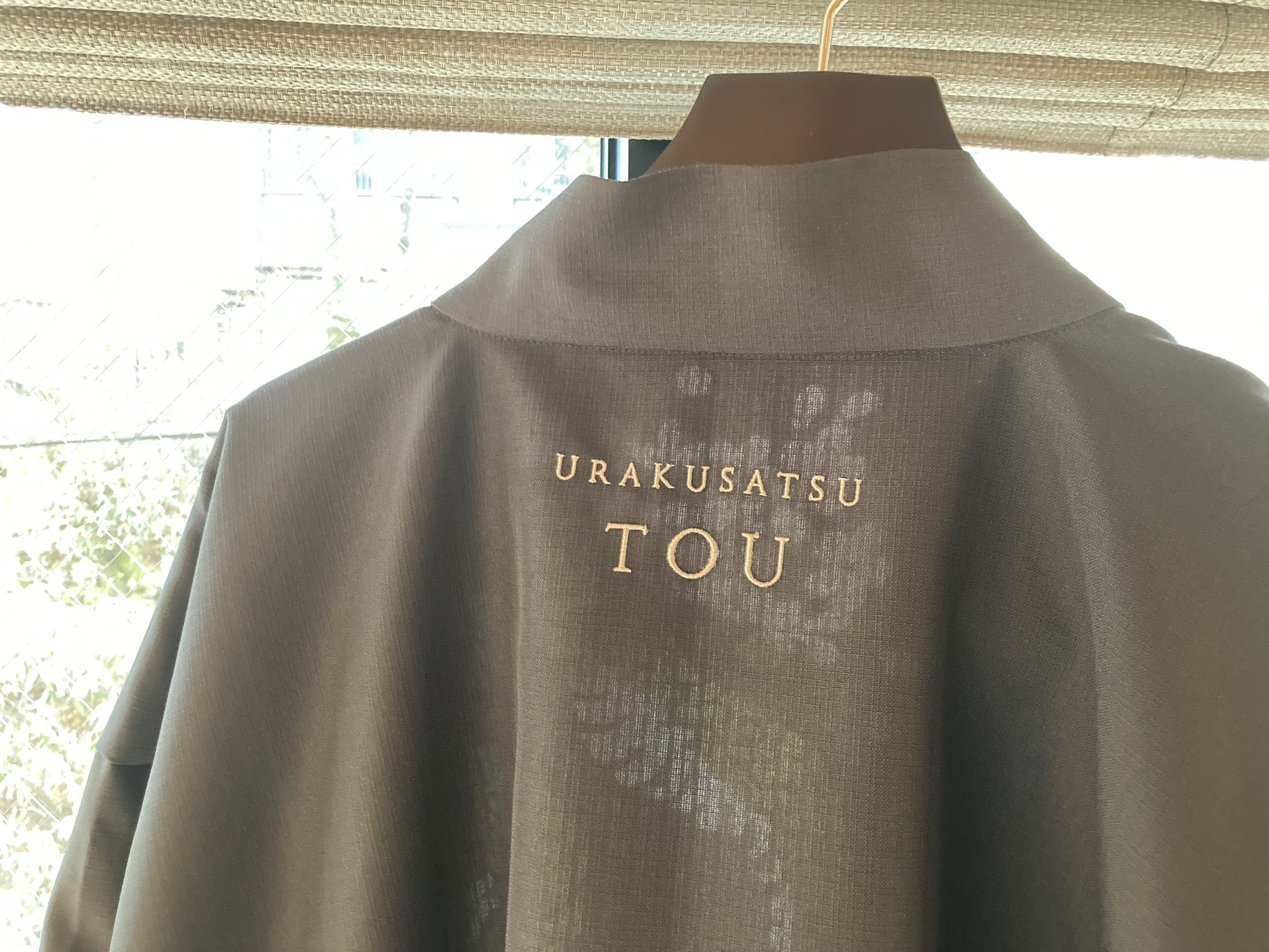 Una prenda con el texto "URAKUSATSU TOU" en la parte trasera.