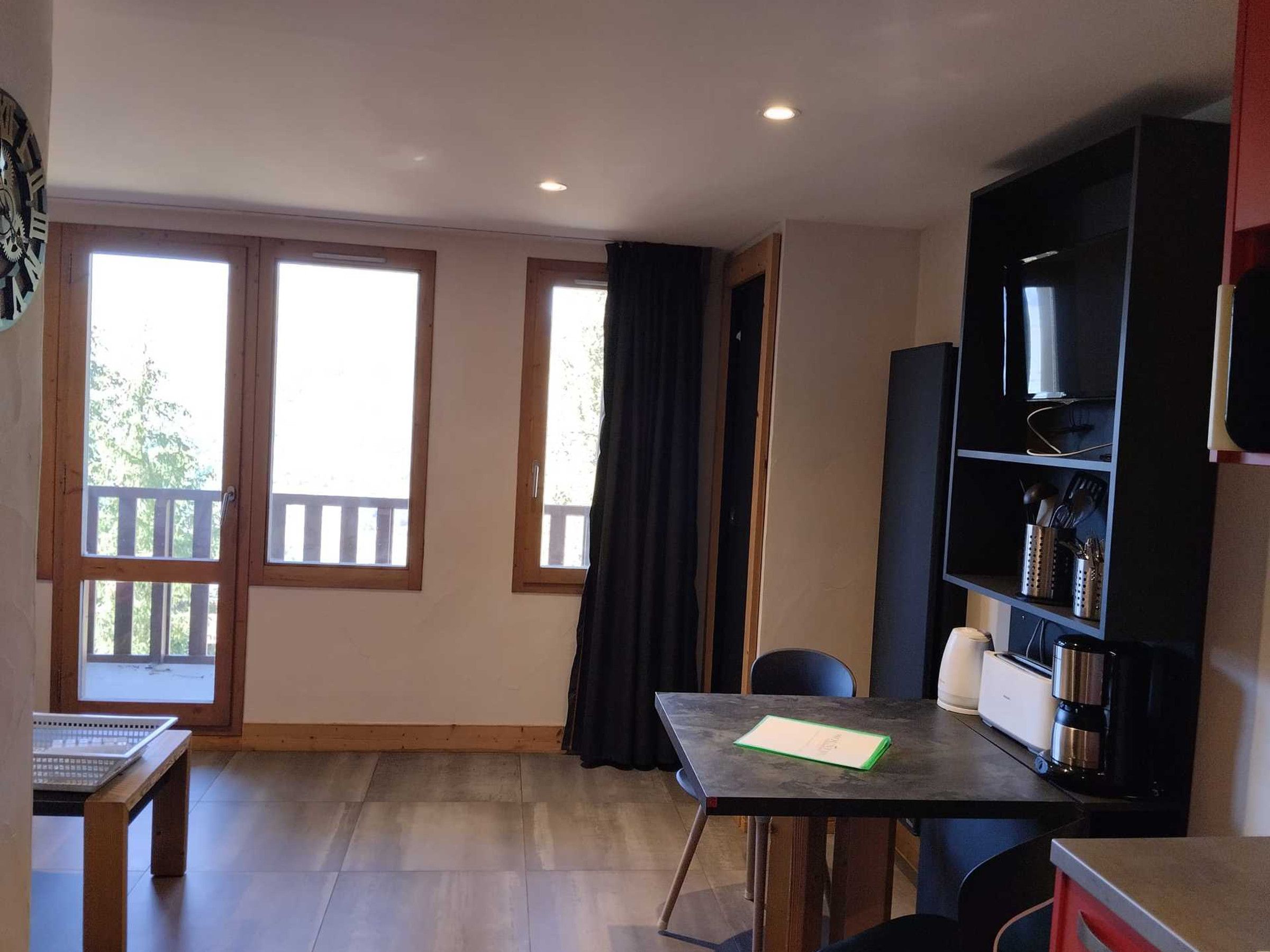 A room with a table, chairs, a bookshelf, and a television.
