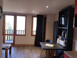 A room with a table, chairs, a bookshelf, and a television. - Renovated studio near slopes with Mont Blanc view (La Plagne Montchavin Les Coches)