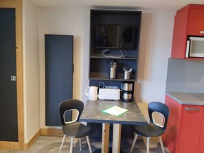 A small dining area with a table, two chairs, a coffee maker, and a microwave above the table. - Renovated studio near slopes with Mont Blanc view (La Plagne Montchavin Les Coches)