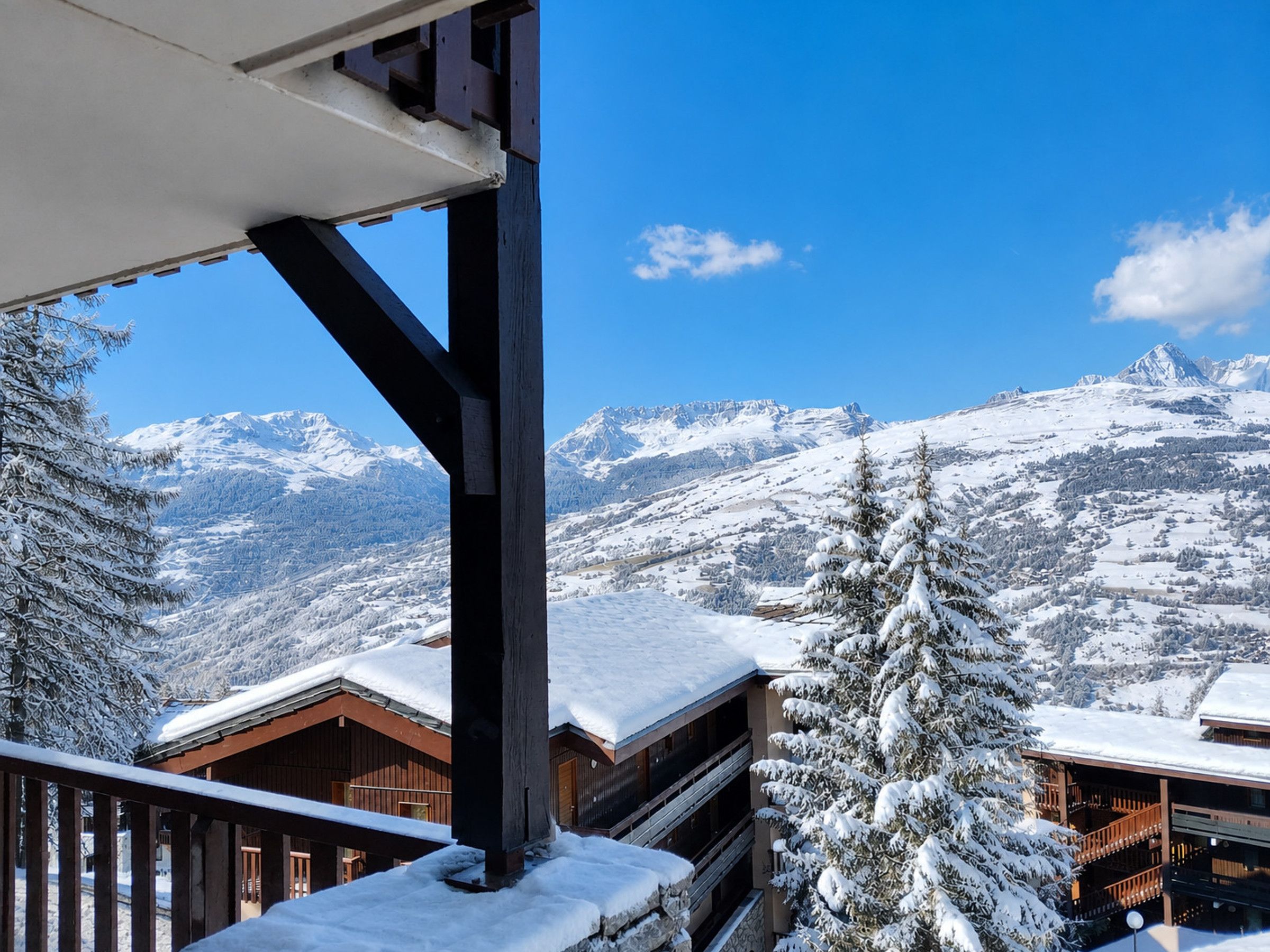 A snow-covered mountain landscape with wooden buildings and a clear blue sky.