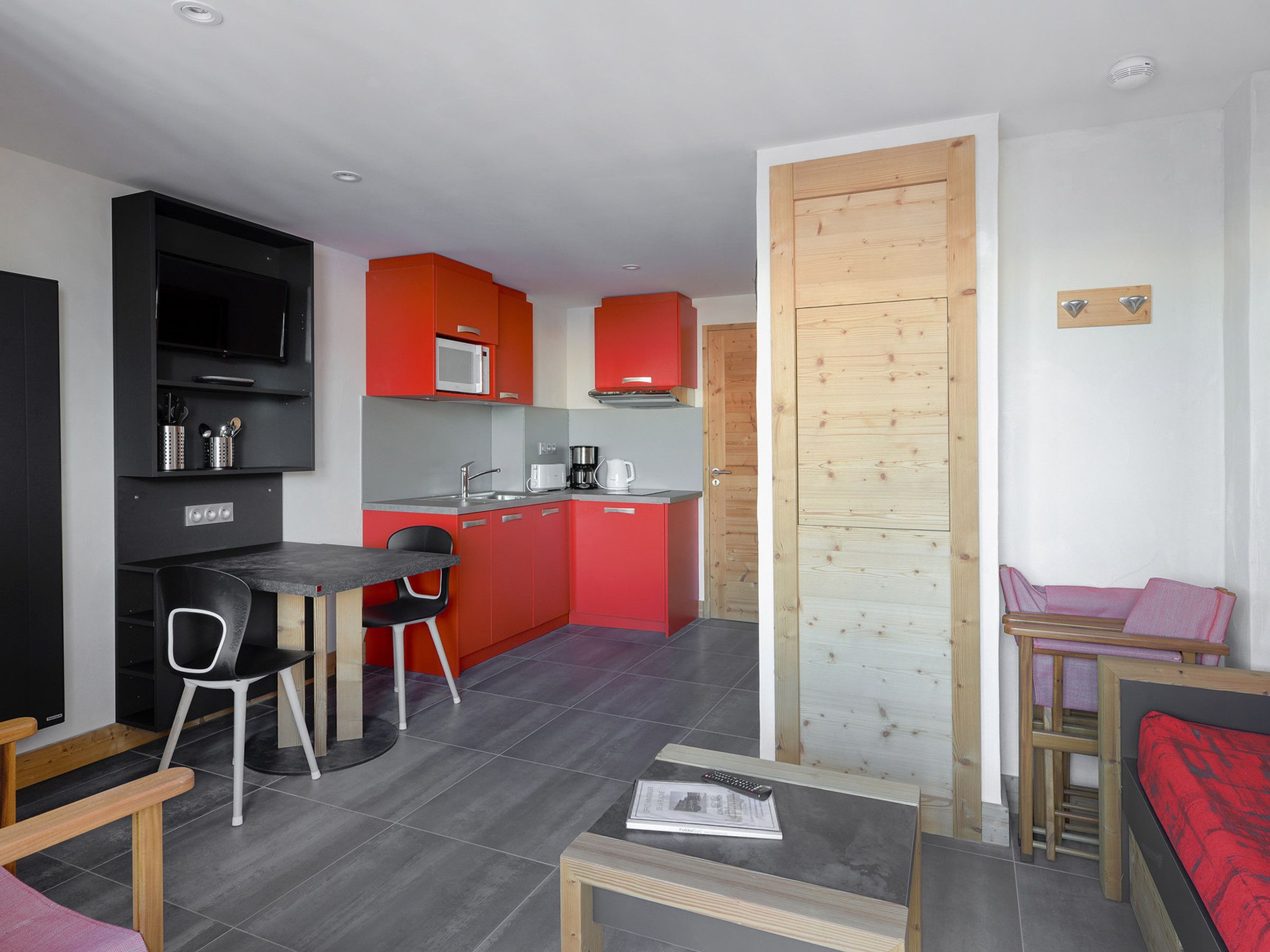 Un espacio habitable compacto con kitchenette, comedor y zona de descanso.