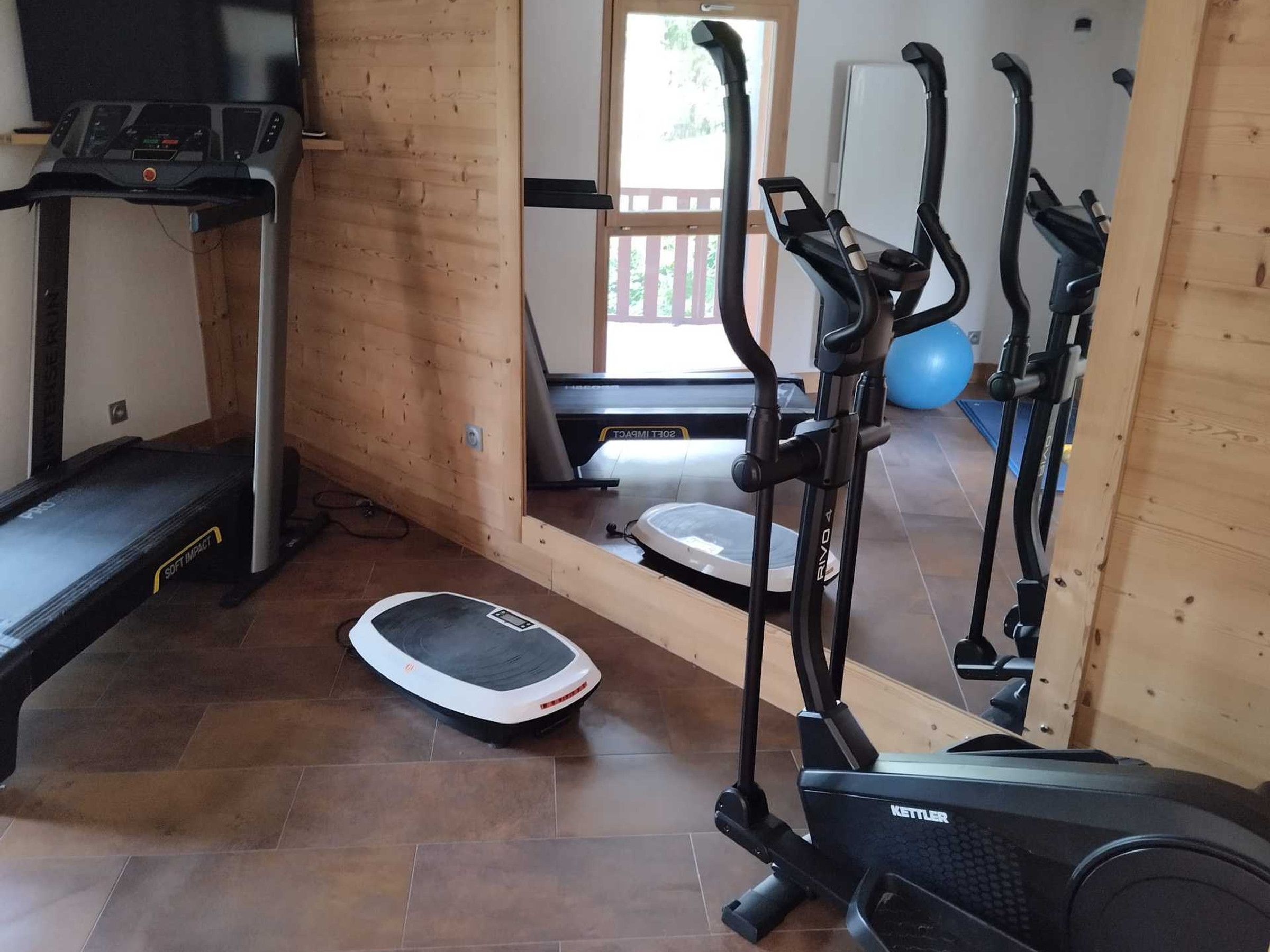 Ein Heimfitnessraum mit Laufband, Crosstrainer und Ergometer.