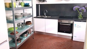 Ett kompakt kök med vita skåp, en svart bänkskiva, en diskho i rostfritt stål och en diskmaskin.